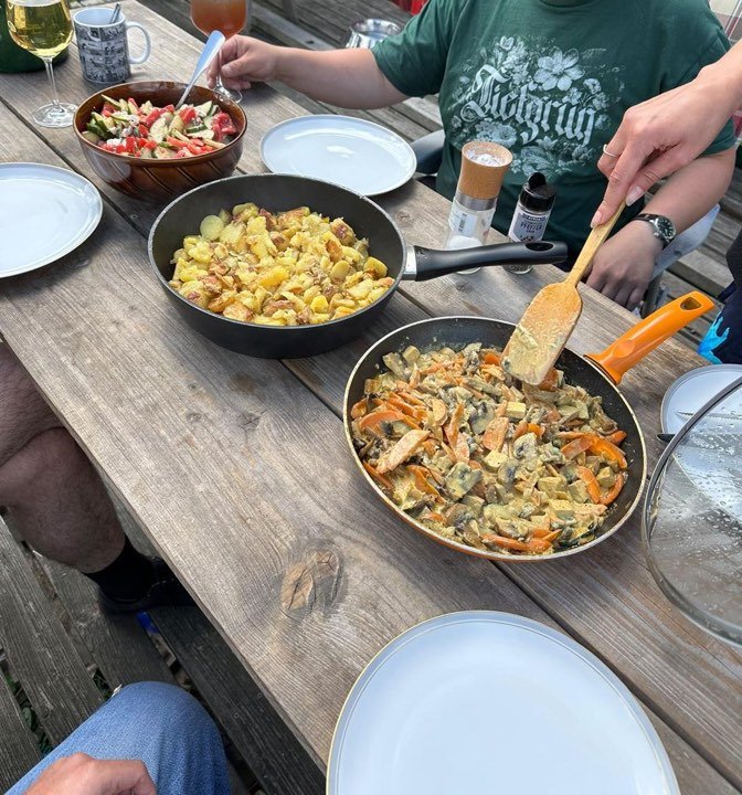 Gedeckter Tisch auf der Terrasse mit Bratkartoffeln, Salat und Gemüsepfanne