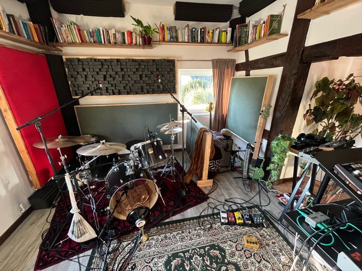 Aufnahmeraum mit Drumset, Teppichen, Bücherregalen und Akustikelementen