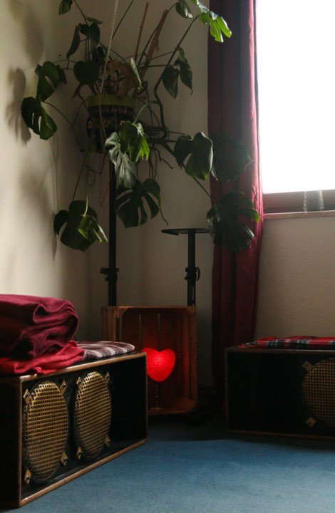 Ecke mit Monstera, Lautsprechern und rotem Herzlicht